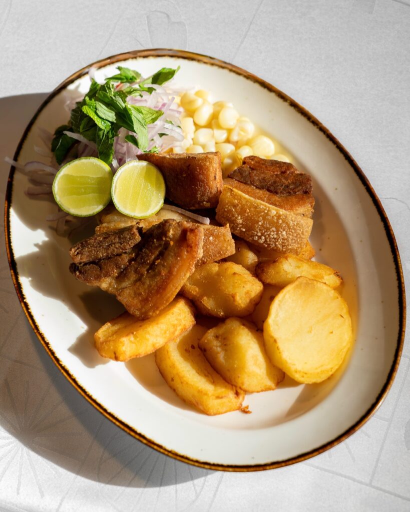Chicharron cusqueno con mote y papa Chicharron cusqueno servido con mote, papa y salsa criolla en Cusco, Peru