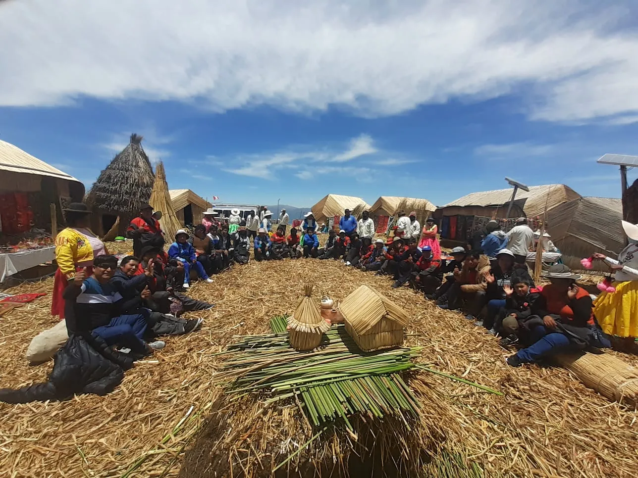 Familias uros y visitantes en una isla flotante de totora, Lago Titicaca Familias uros y visitantes en una isla flotante de totora, Lago Titicaca